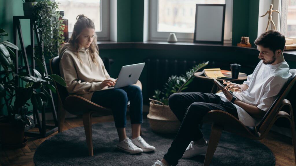 A picture of a man and a woman working on their laptop