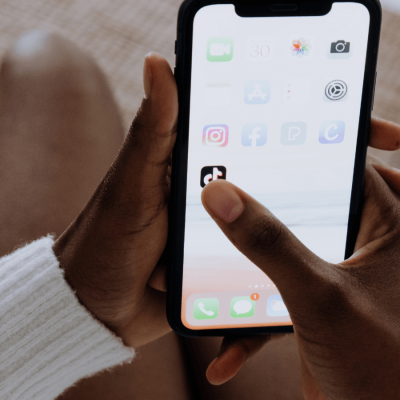 A woman clicking on the TikTok app on her smartphone